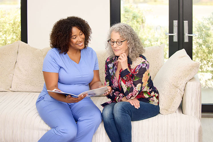 clinical employee reading booklet with patient on a couch